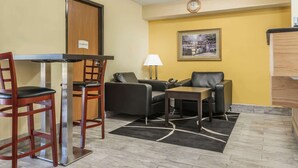 A hotel room with a dining area, two sofas, a table, and a lamp.