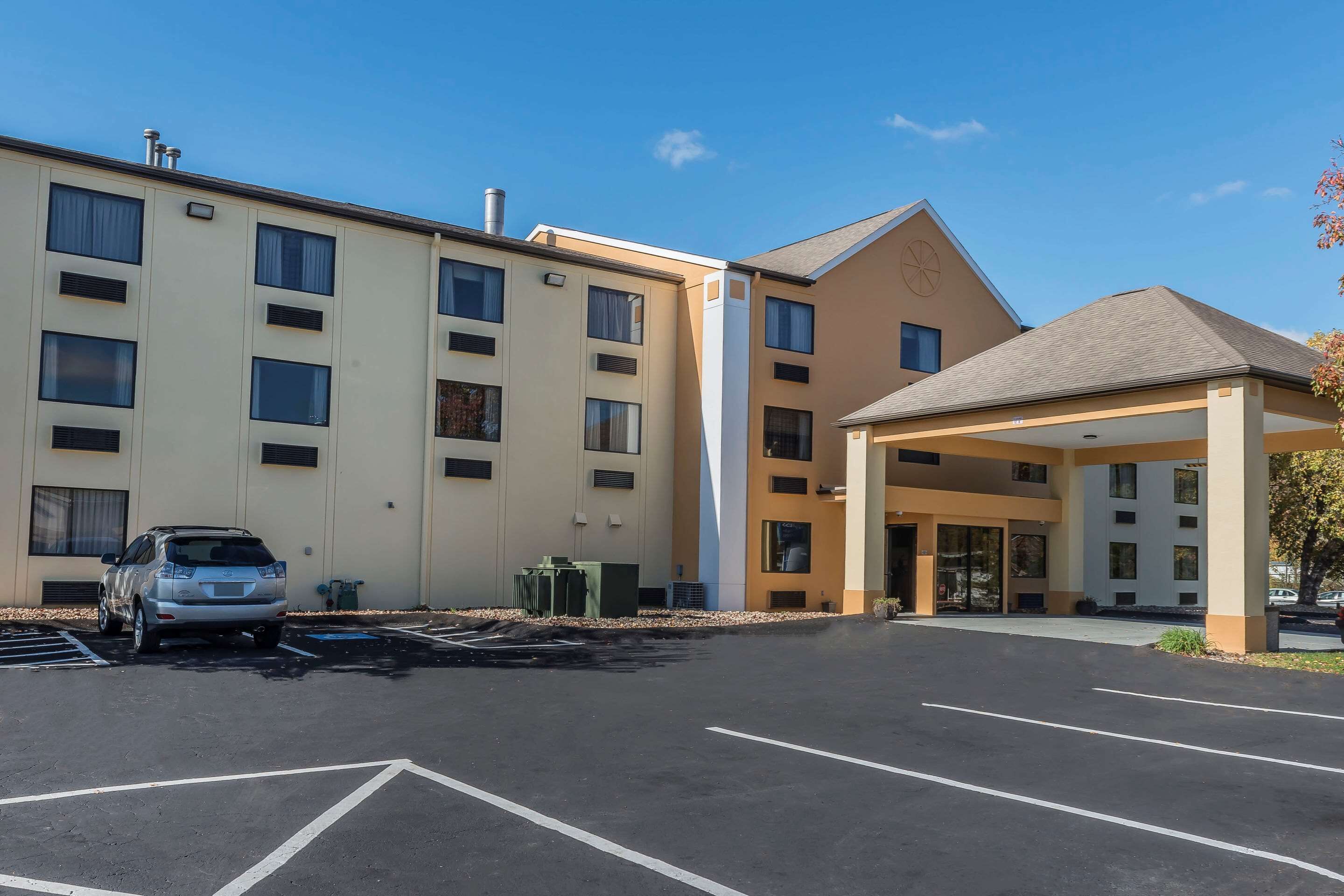 Un hôtel doté d’une entrée abritée, de nombreuses fenêtres et d’un parking où sont stationnées quelques voitures.