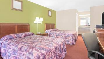 A hotel room with two beds, a desk, a chair, and a television.
