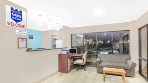 Un área de recepción con escritorio, computadora y un cartel que indica habitaciones para no fumadores.