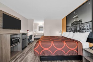 Habitación de hotel con cama, escritorio, televisión de pantalla plana, microondas y refrigerador.
