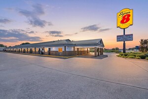 Un motel Super 8 con un amplio estacionamiento y cielo despejado.