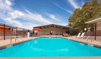 Una piscina con socorrista, sillas de descanso y una zona de estar cubierta.