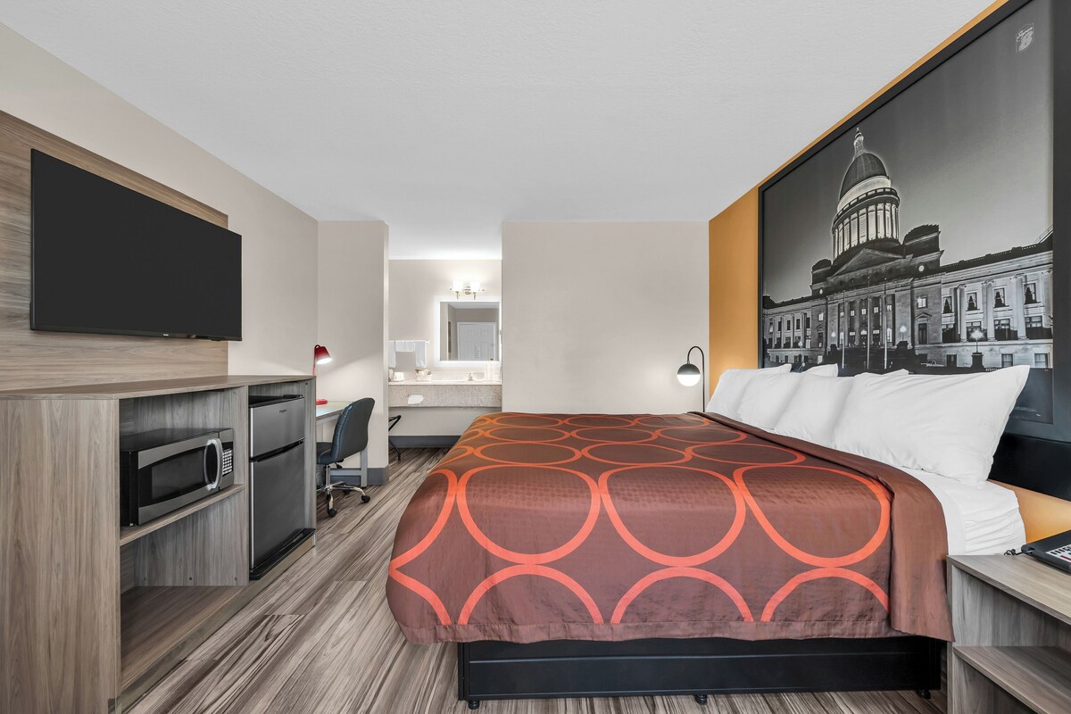 Habitación de hotel con cama, escritorio, televisor de pantalla plana, microondas y refrigerador.