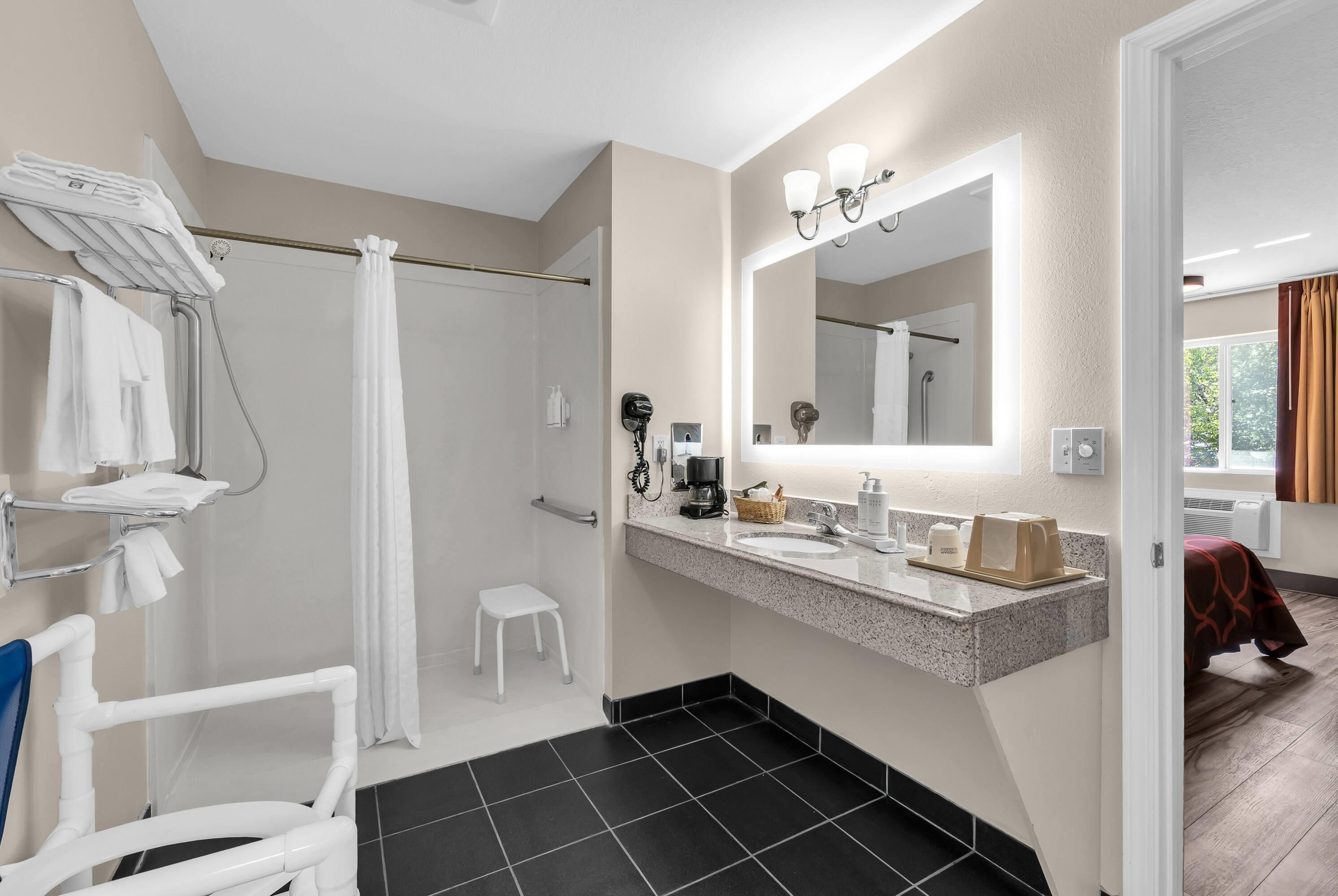 A modern bathroom with a shower, a sink with a mirror, and a toilet.