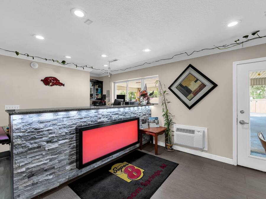 Un espace d’accueil avec un comptoir en pierre, une horloge rouge et un tableau encadré au mur.
