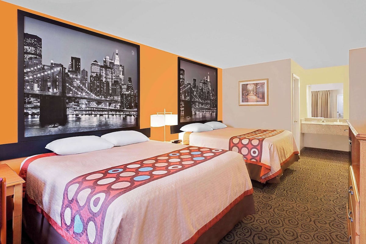 A hotel room with two beds, a television, a desk, and a bathroom.