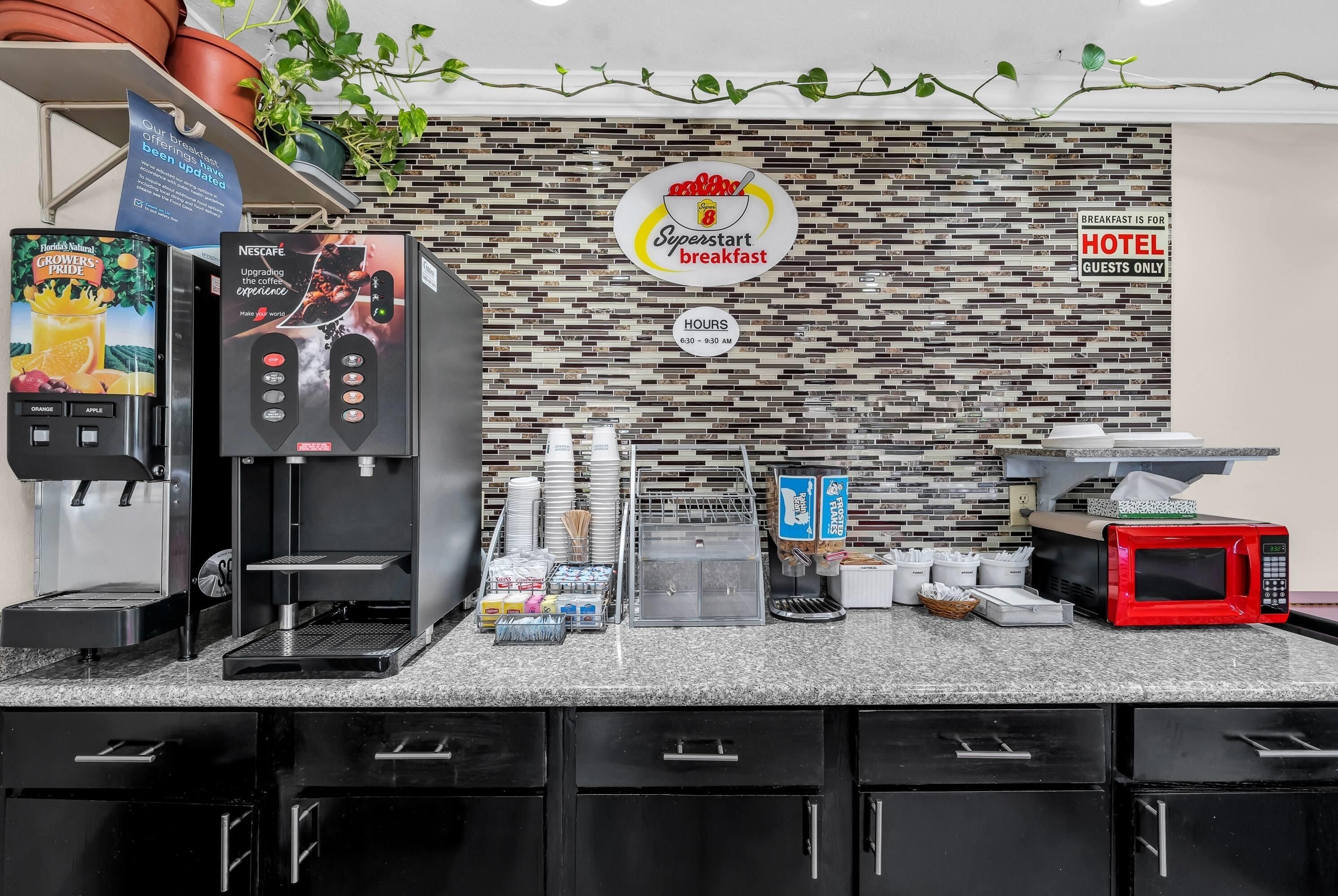 A breakfast area with a coffee machine, a sign indicating Superstart breakfast hours, and a sign for hotel guests only.