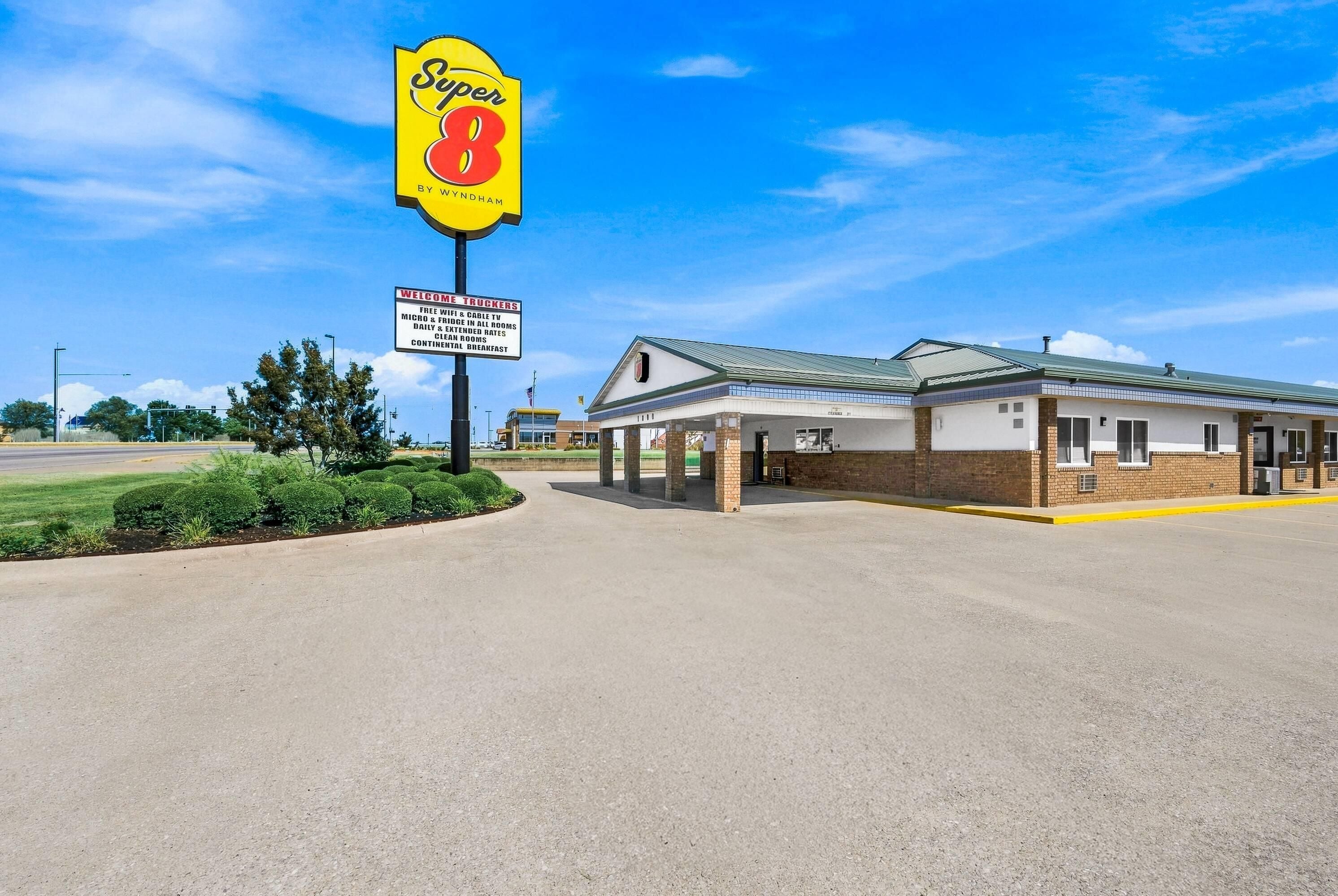 A Super 8 motel with a clear sky, a welcoming sign for truckers, and a simple building structure.
