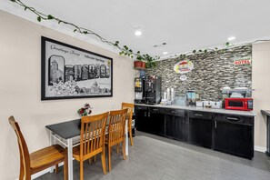 Una cocina moderna con zona de comedor, que incluye un cartel con un paisaje urbano enmarcado, un letrero de desayuno y un letrero de desayuno Superstart.