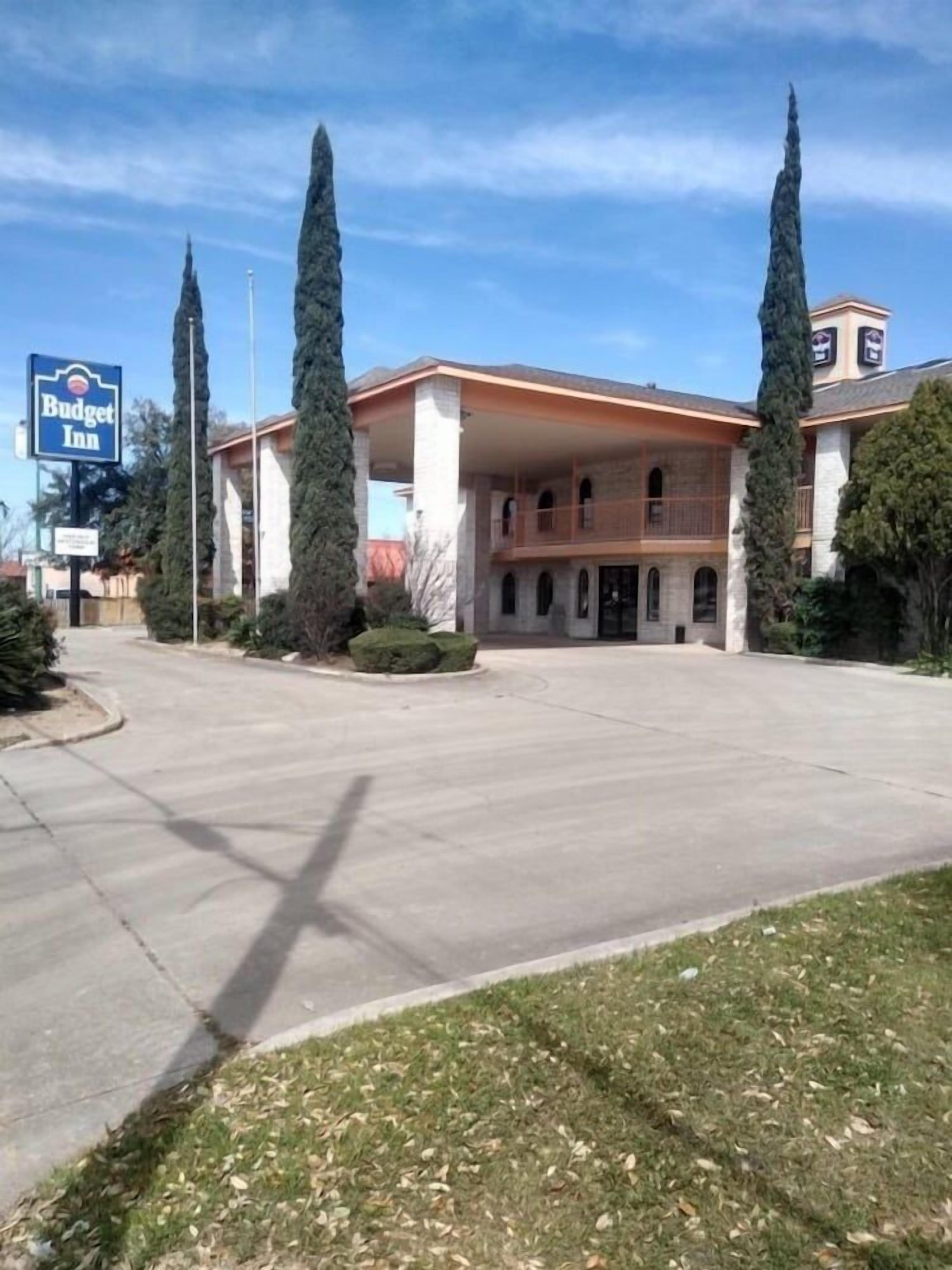 A Budget Inn with a central courtyard, a parking lot, and a clear sky.