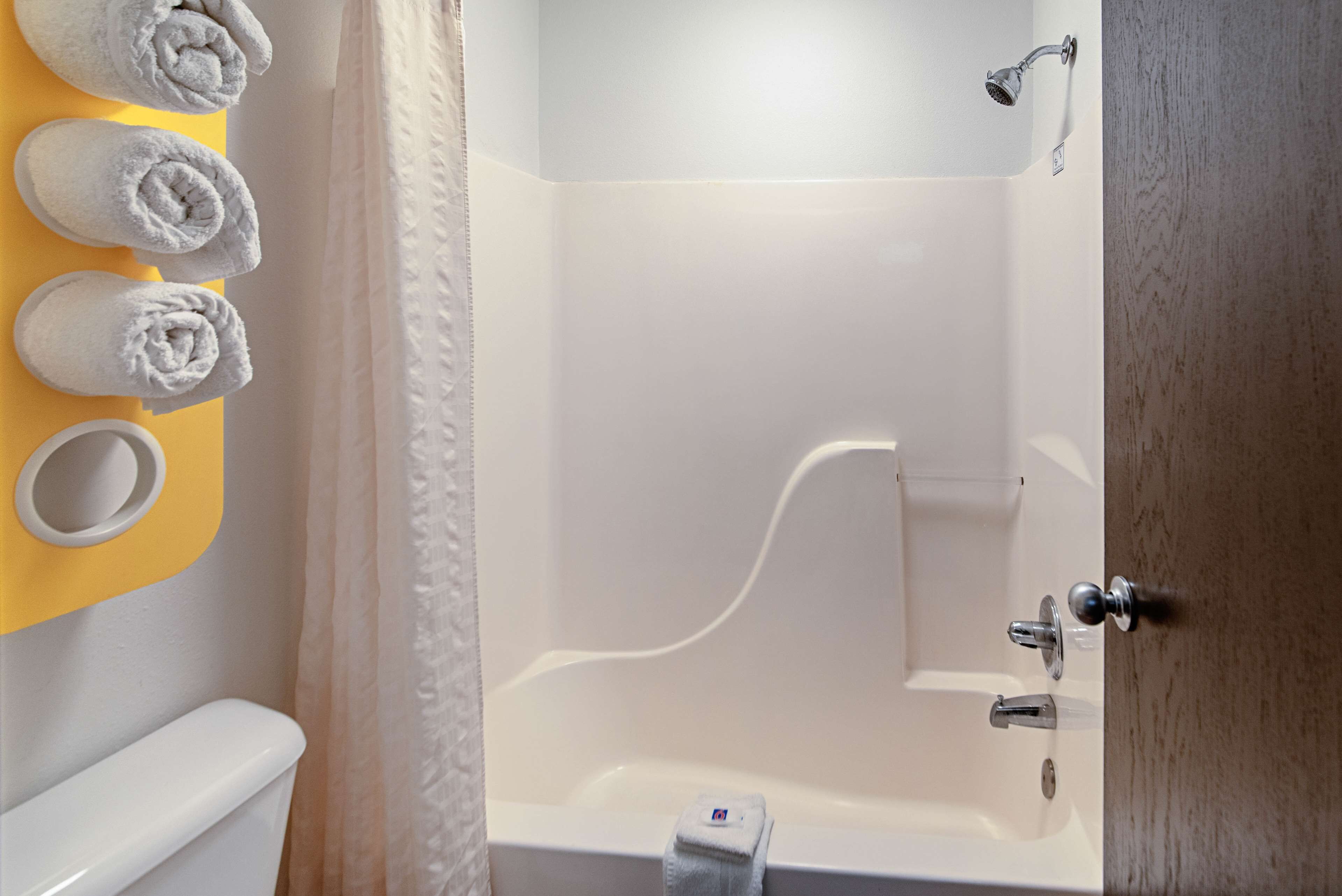 A bathroom with a bathtub, a toilet, and a sink. There are towels hanging on a yellow wall.