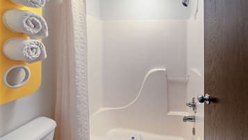 A bathroom with a bathtub, a toilet, and a sink. There are towels hanging on a yellow wall.