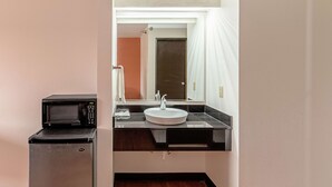 A compact bathroom with a sink, mirror, and a microwave on a small cabinet. - Motel 6 Lebanon, IN (Lebanon)