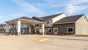 A hotel with multiple buildings, a covered parking area, and a clear sky. - Motel 6 Lebanon, IN (Lebanon)