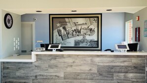 Un comptoir d’accueil orné d’une photo historique encadrée, d’une horloge et d’un panneau indiquant « dépôt du courrier sortant ».