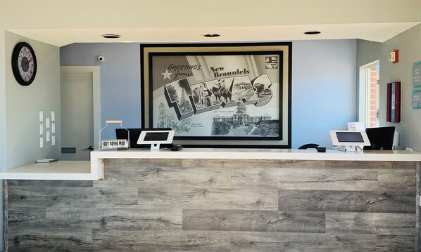 Welcome to our reception area, featuring a digital monitor and a mailbox for outgoing mail, surrounded by a large framed poster showcasing local history.