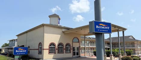 Un edificio con un letrero que dice 'Baymont by Wyndham' y un acceso cubierto.