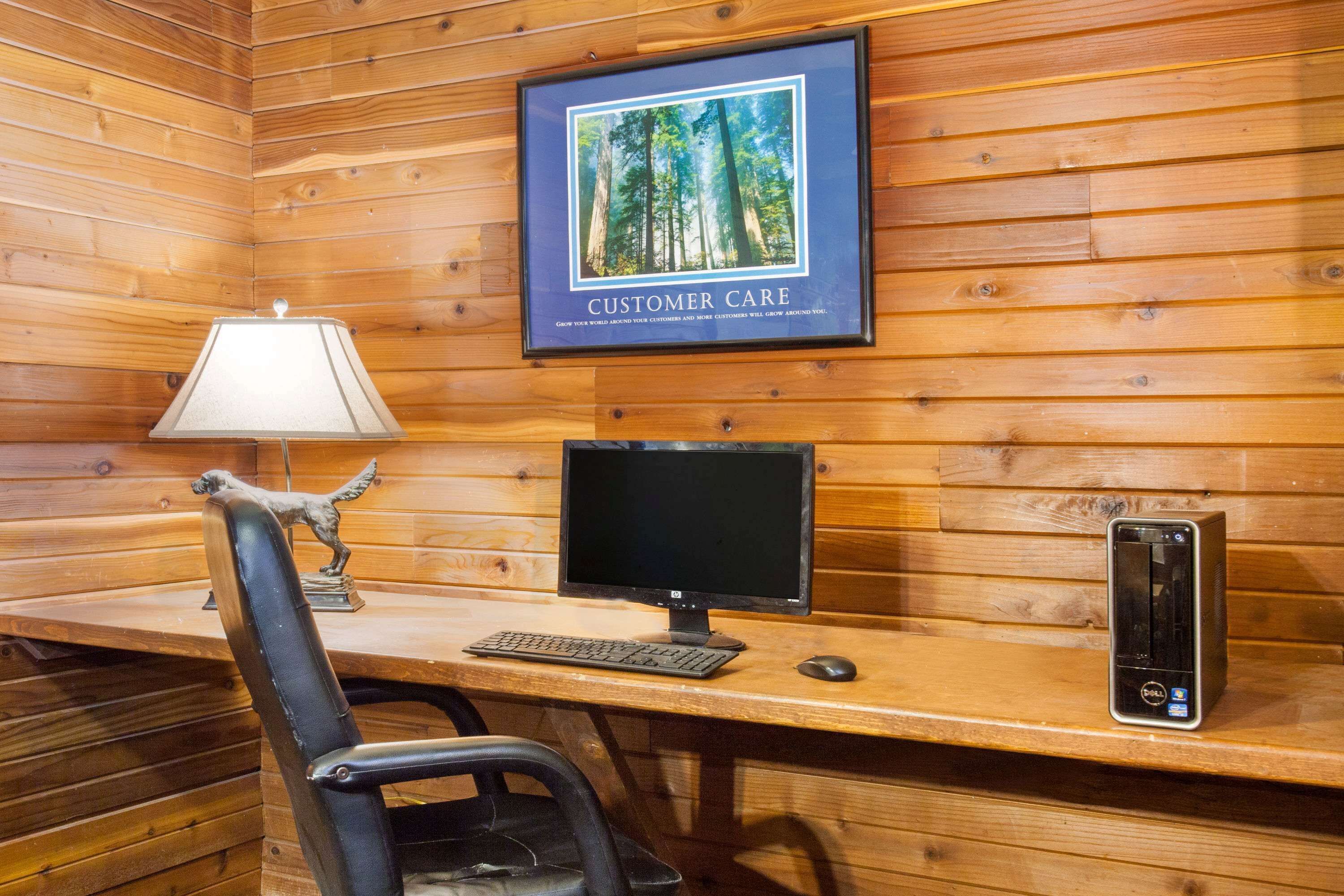 A wooden cabin interior with a desk, computer, and a framed picture on the wall.