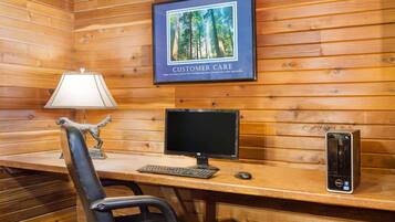 A wooden cabin interior with a desk, computer, and a framed picture on the wall.