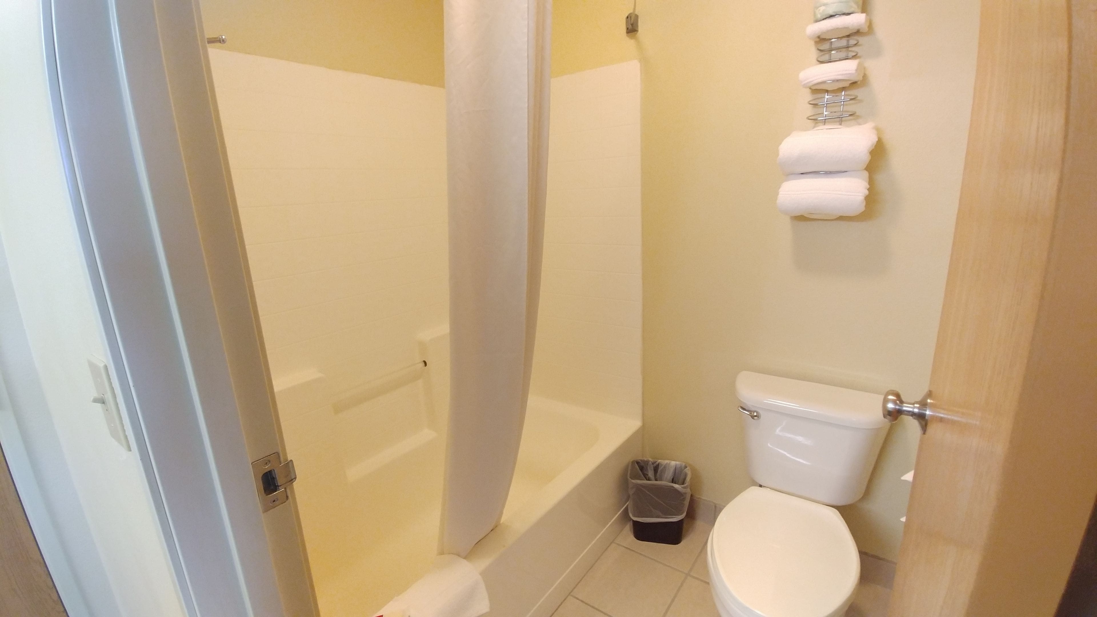 Ein Badezimmer mit Dusche, Toilette und Mülleimer.