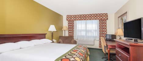 A hotel room with a bed, desk, chair, television, and a window with curtains.