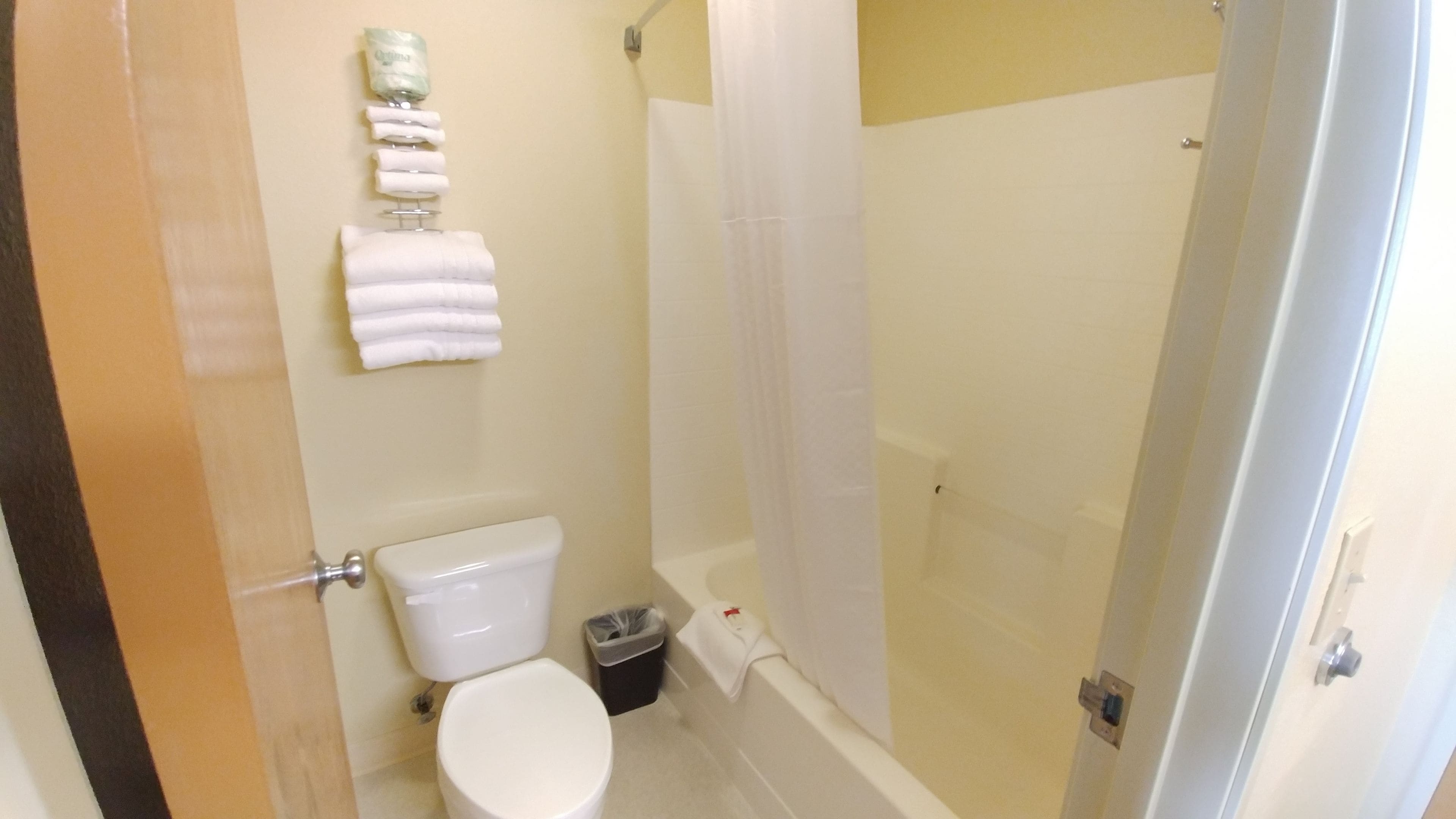 Une salle de bain équipée de toilettes, d’une douche et d’un porte-serviettes avec des serviettes pliées.