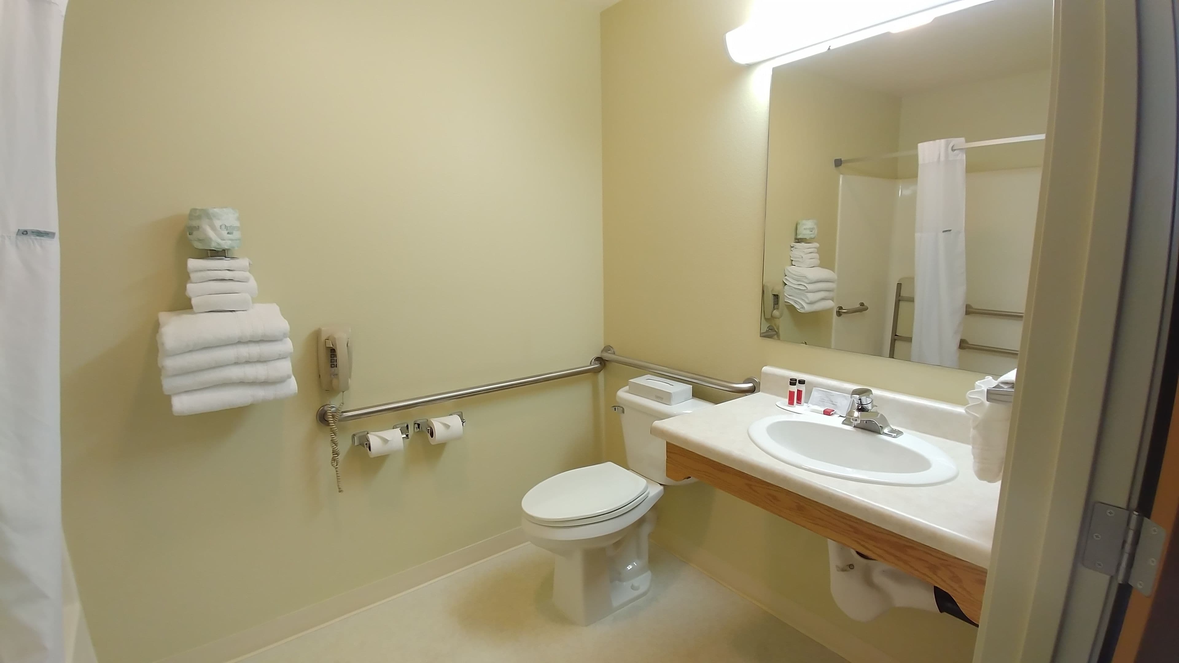 Une salle de bain équipée de toilettes, d’un lavabo et de barres d’appui.