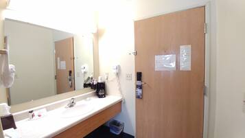 A hotel bathroom with a sink, mirror, and wooden door.