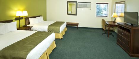 A hotel room with two beds, a desk, a chair, a television, and a mirror.