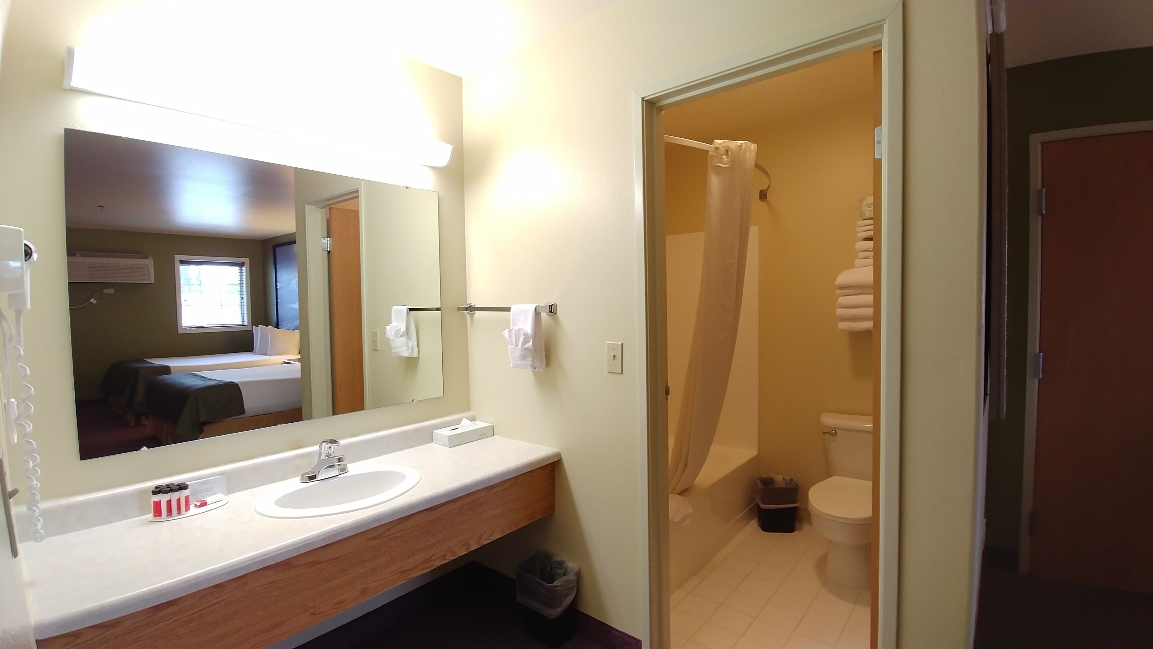 A bathroom with a sink, mirror, and shower.