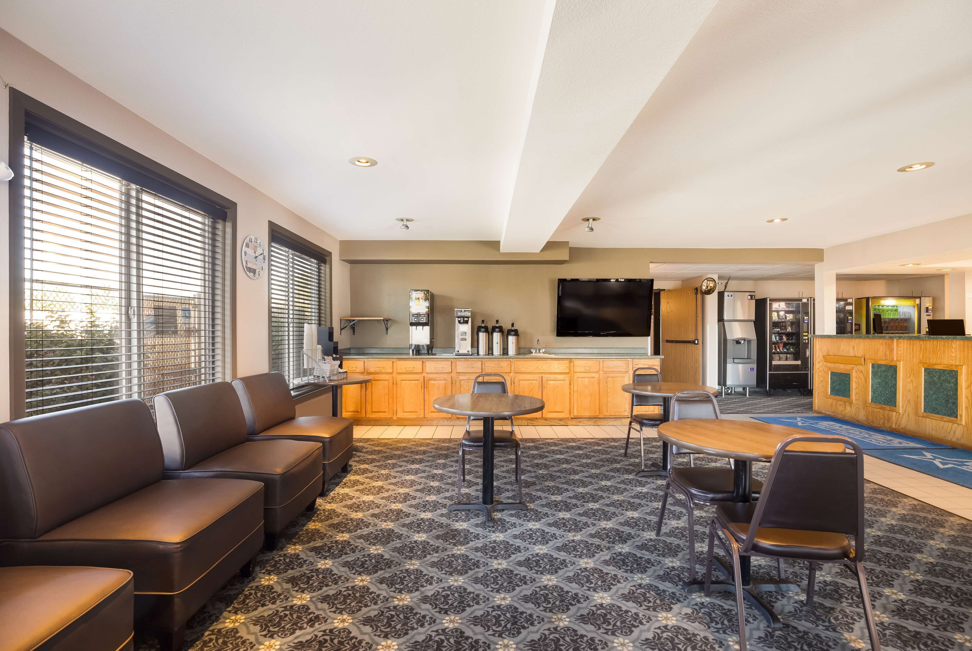 A modern hotel lobby with a seating area, a kitchen, and a bar.