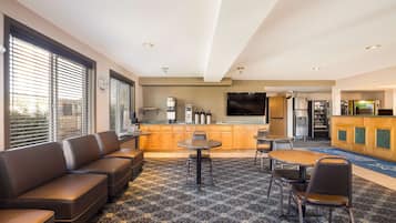 A modern hotel lobby with a seating area, a kitchen, and a bar.