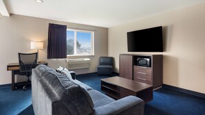 Habitació d'hotel amb sofà, escriptori, cadira, televisió i armari.