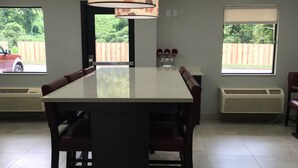 A dining area with a table and chairs, a ceiling light fixture, and windows with views of a backyard. - Red Roof Inn PLUS+ Birmingham East - Irondale/ Airport (Birmingham)