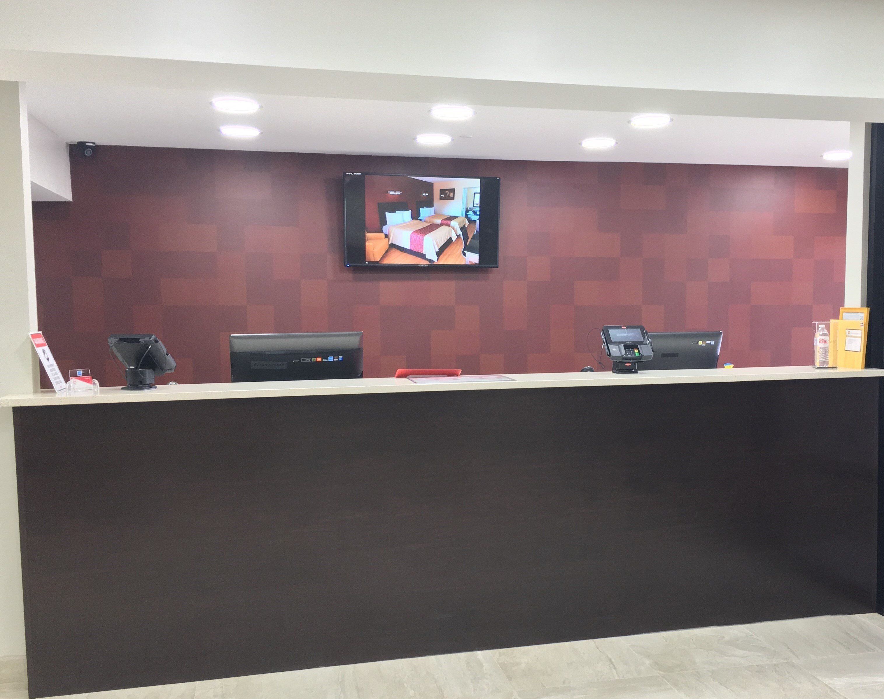 A reception desk with a flat-screen TV mounted above it, a cash register, and a computer monitor.