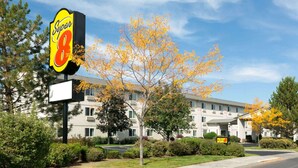 Un motel Super 8 con un letrero grande, rodeado de árboles otoñales y un edificio de varios pisos.