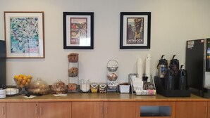 Una barra de desayuno con un refrigerador, máquinas de café y diversos recipientes de comida.