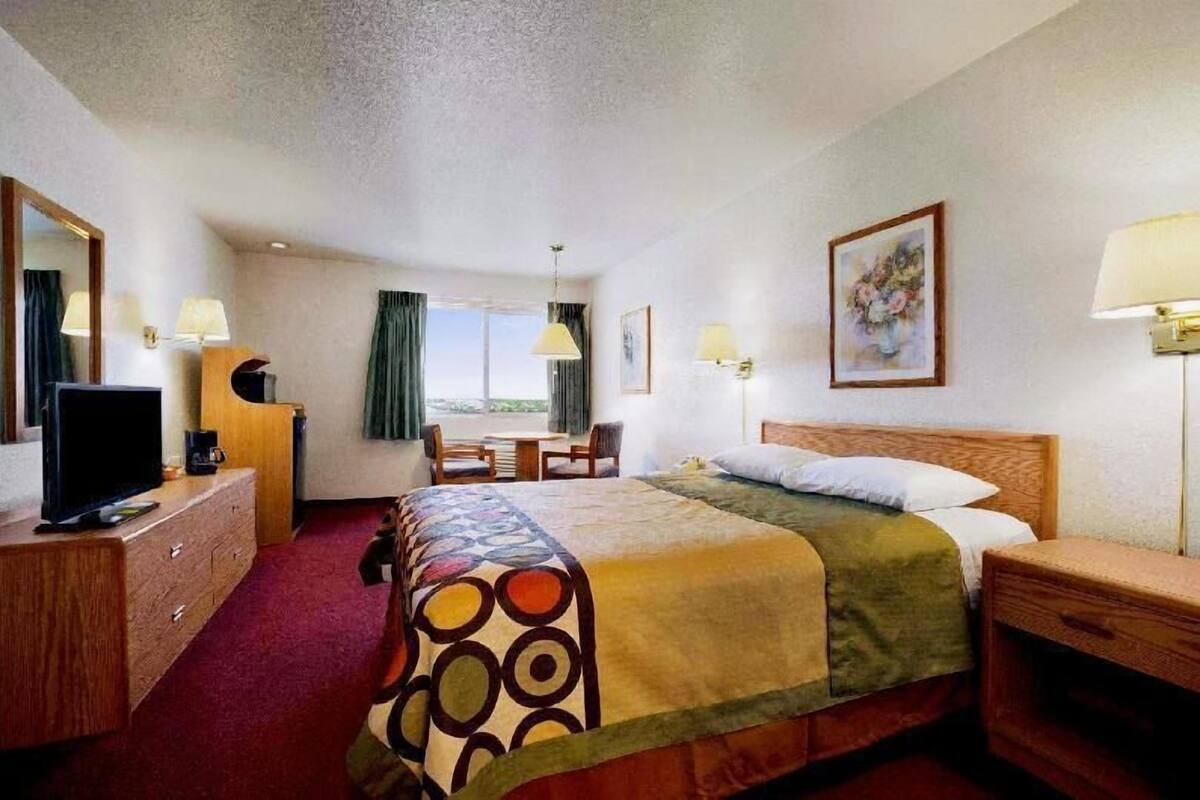 Ein Hotelzimmer mit Bett, Schreibtisch, Fernseher und einem Fenster mit Vorhängen.