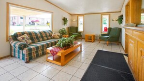 A cozy living room with a plaid sofa, a wooden coffee table, and a green armchair. - FairBridge Inn Express Merrillville (Merrillville)