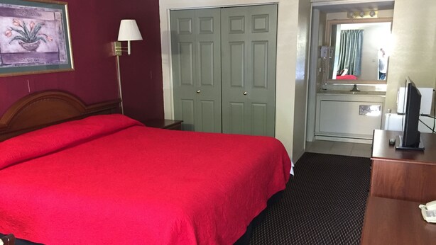 A hotel room with a large bed, a desk with a computer, a mirror, and a door leading to a bathroom. - FairBridge Inn Express Merrillville (Merrillville)