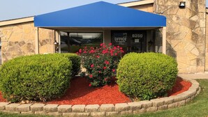 A building with a stone facade, a blue awning, and a red flower bed with red mulch. - FairBridge Inn Express Merrillville (Merrillville)