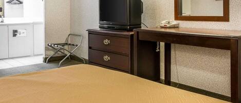 Quarto de hotel com cama, cómoda de madeira com televisão, espelho e telefone.