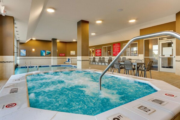 Un bain à remous doté d’une rambarde en métal, entouré d’une zone carrelée avec des chaises et des tables.
