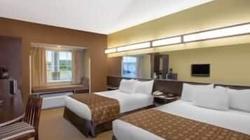 A hotel room with two beds, a desk, a chair, a TV, and a window with curtains.