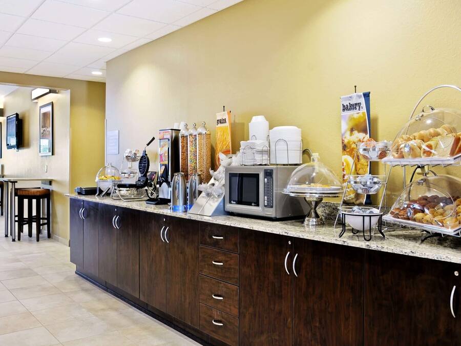 A breakfast bar with a microwave, coffee maker, and various food items.