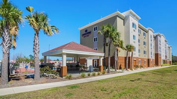 A hotel with a covered outdoor area, palm trees, and a clear blue sky.