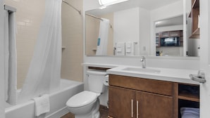 A bathroom with a bathtub, toilet, and vanity with a mirror. - Candlewood Suites Pensacola - University Area by IHG (Pensacola)