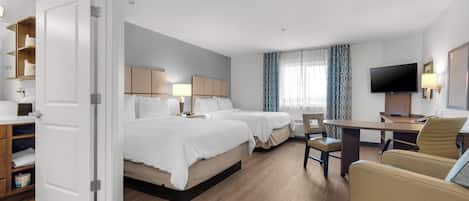 A hotel room with two beds, a desk, a chair, a TV, and a wardrobe.