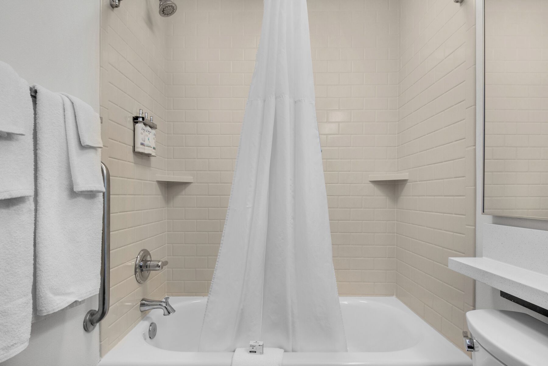 A modern bathroom with a bathtub, a shower curtain, and a toilet.